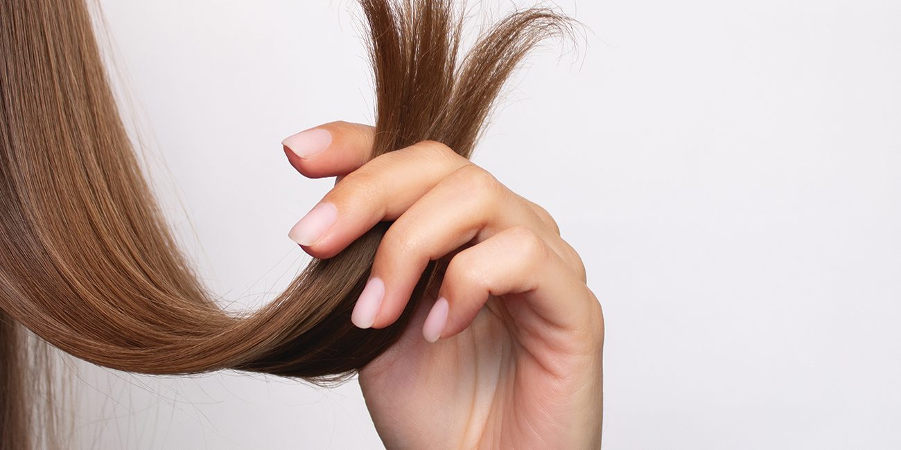 A view of long, auburn hair, comparing healthy, trimmed hair on the left with damaged hair on the right.