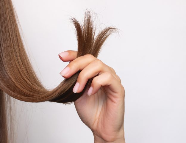 A view of long, auburn hair, comparing healthy, trimmed hair on the left with damaged hair on the right.