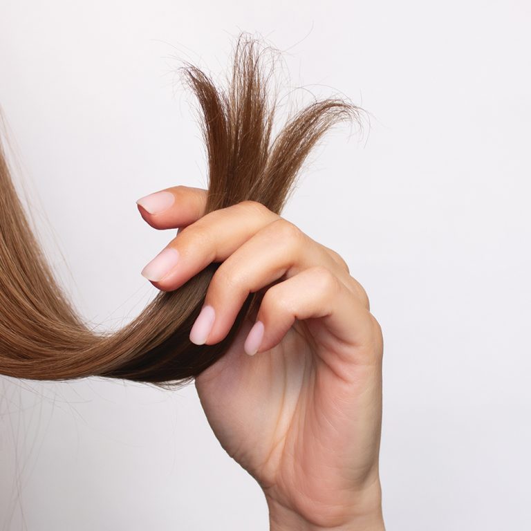A view of long, auburn hair, comparing healthy, trimmed hair on the left with damaged hair on the right.