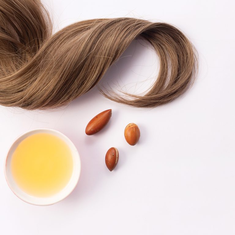What-does-argan-oil-do-for-your-hair : A woman in a towel examines the dry, brittle ends of her hair after a shower.